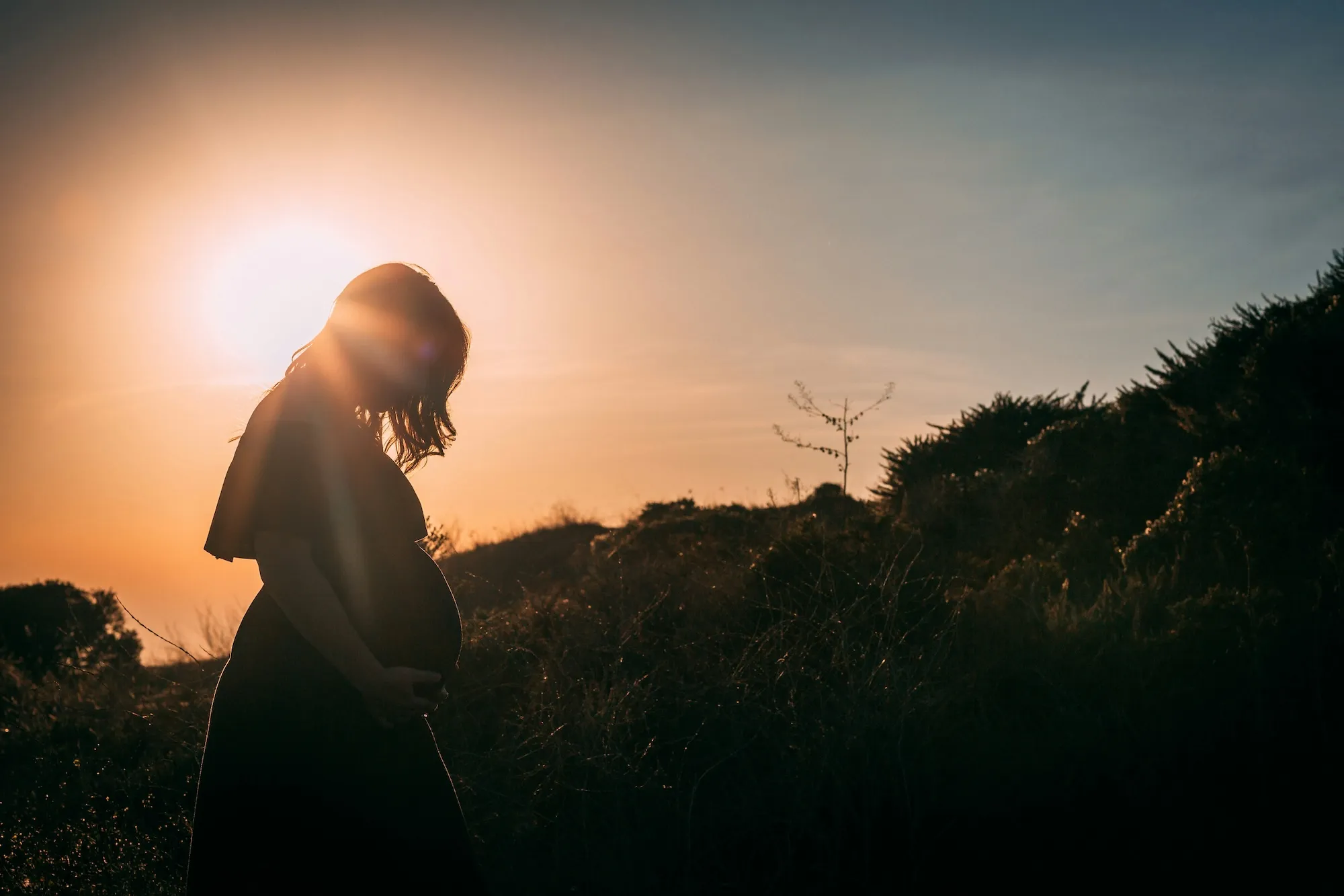 Femme enceinte en silhouette au coucher du soleil
