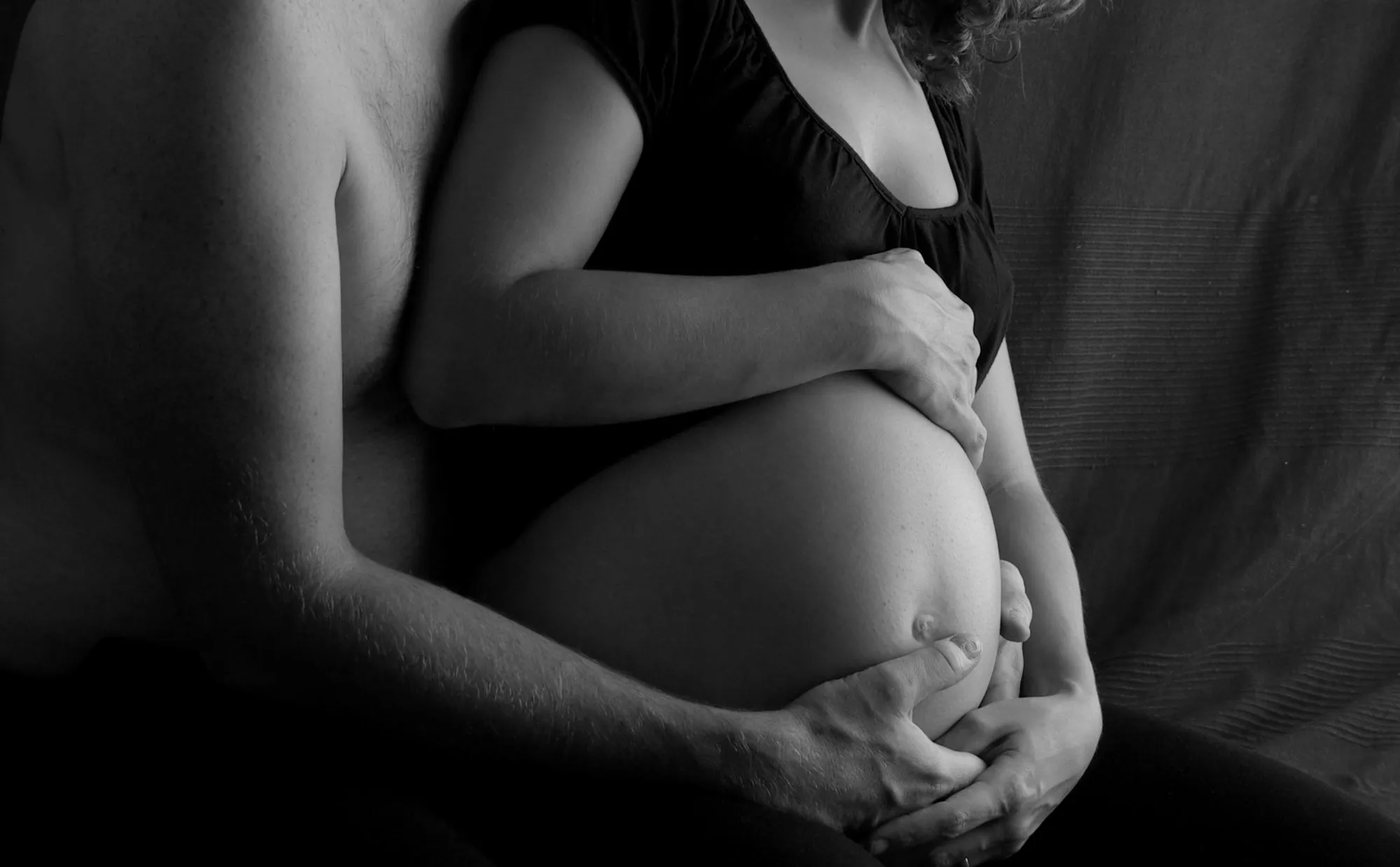 Couple enlacé, mains sur le ventre de la future mère