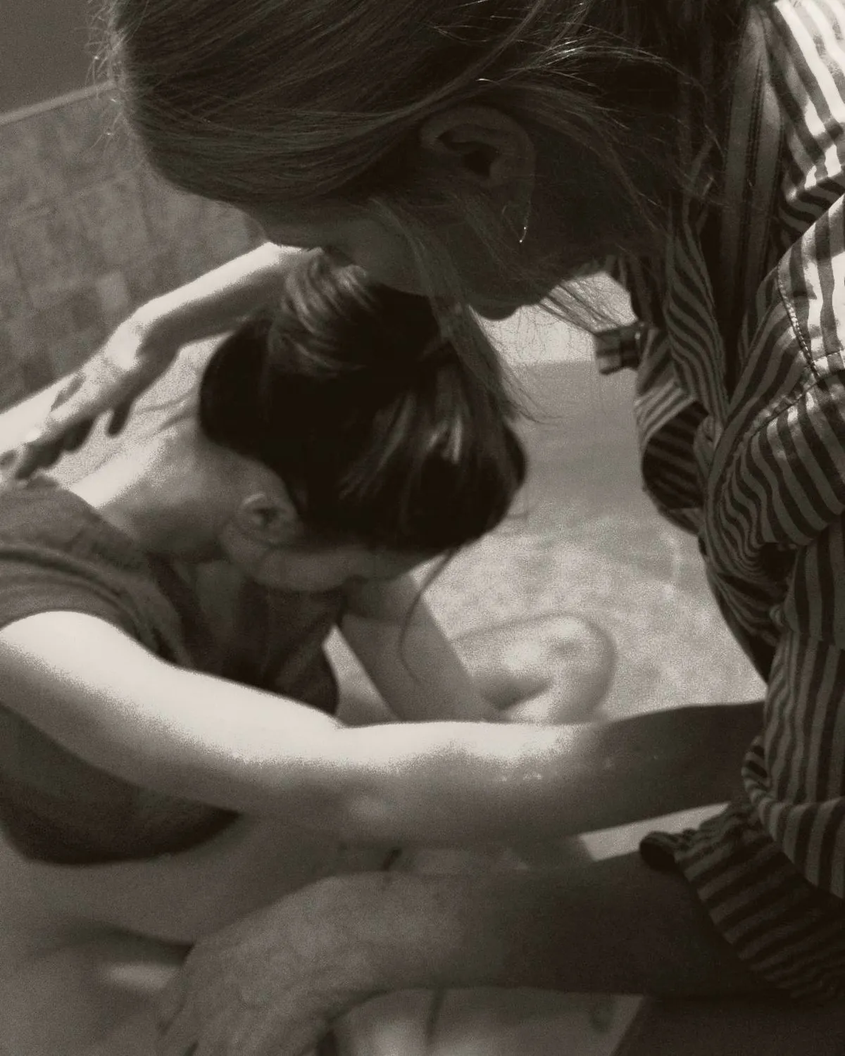 Femme penchée sur une femme en travail à la maison, une main posée sur son épaule