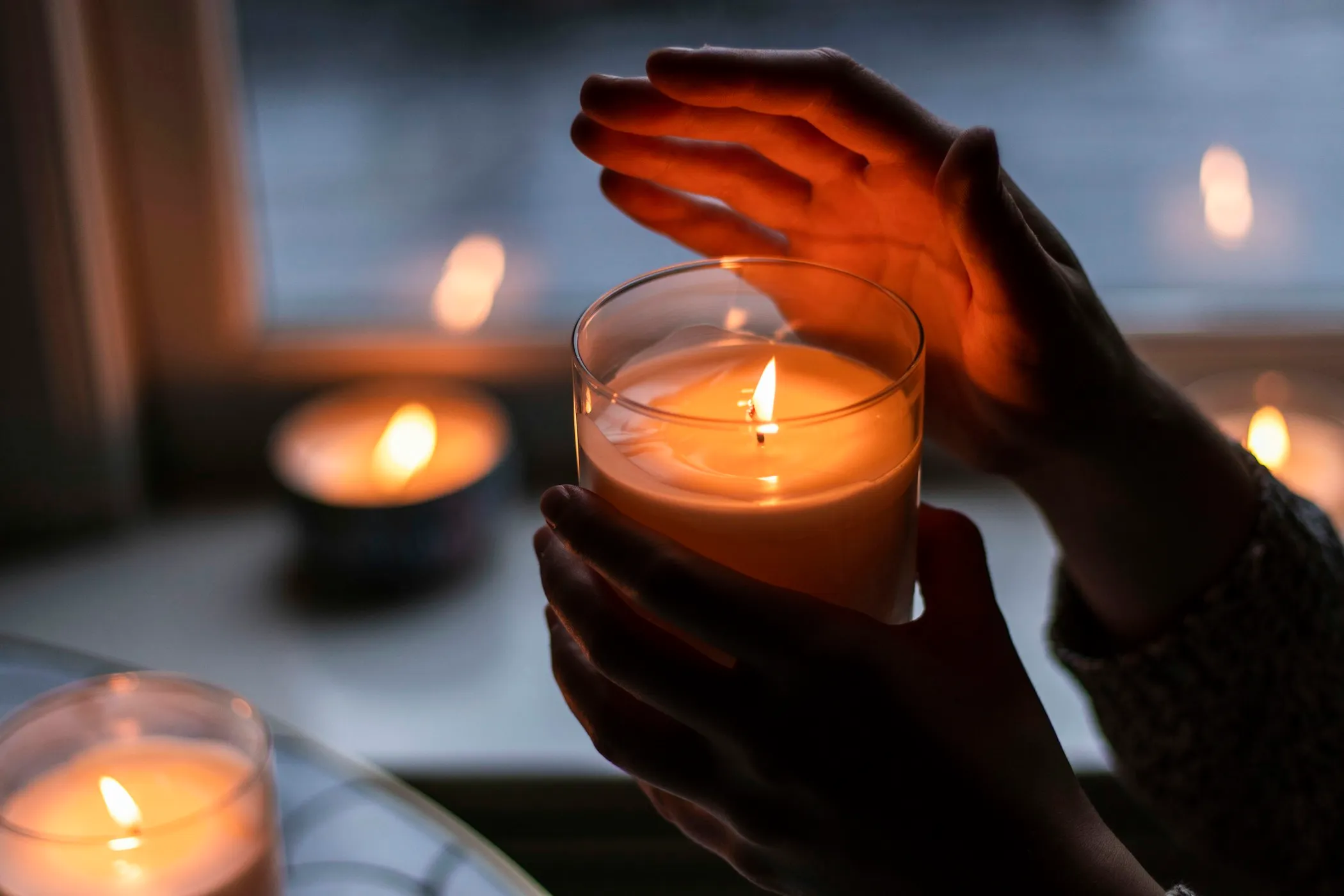 Mains entourant une bougie allumée
