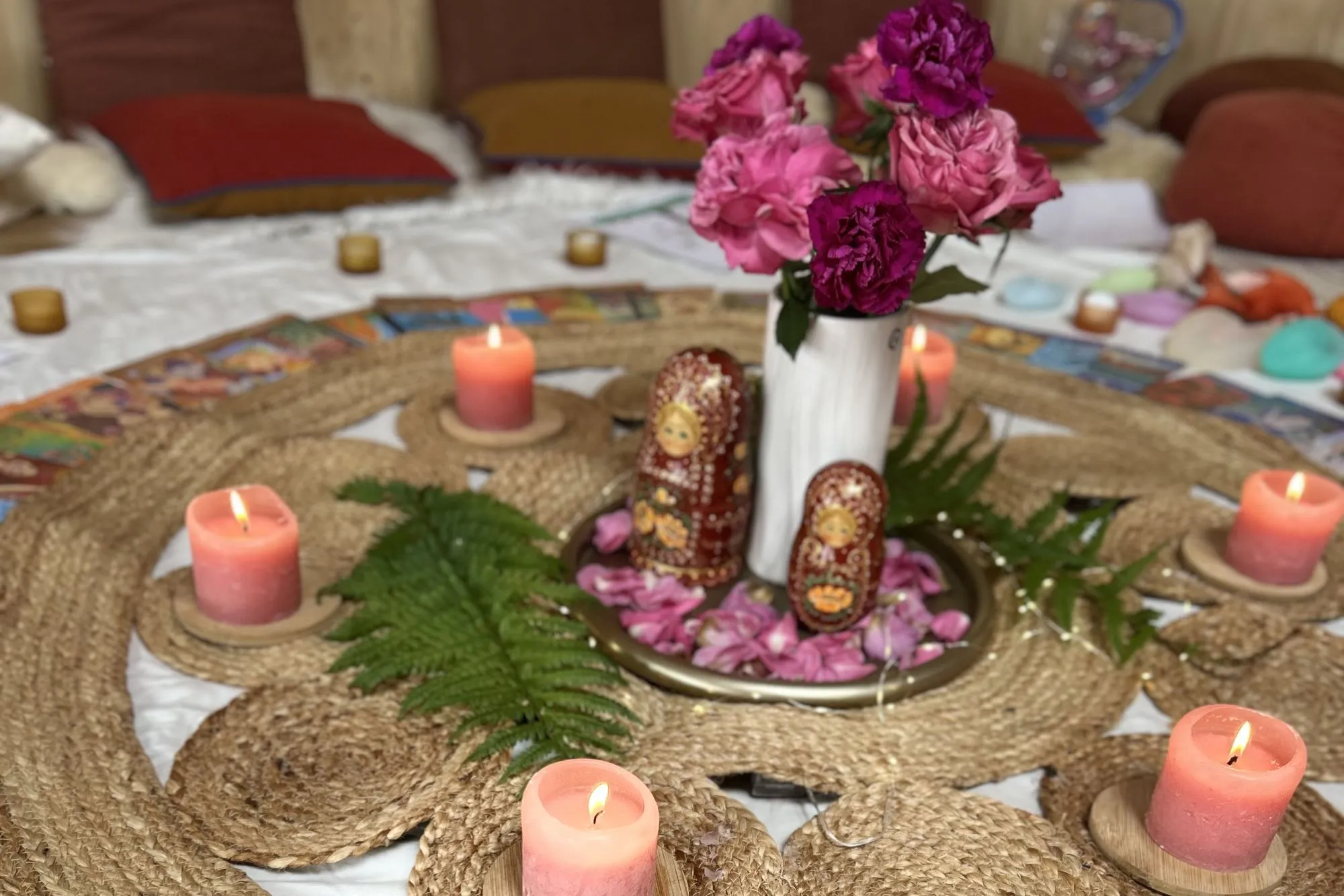 Autel d’un Cercle Rose : roses, poupées russes et fougères au centre, entourés de bougies roses et de cartes illustrées