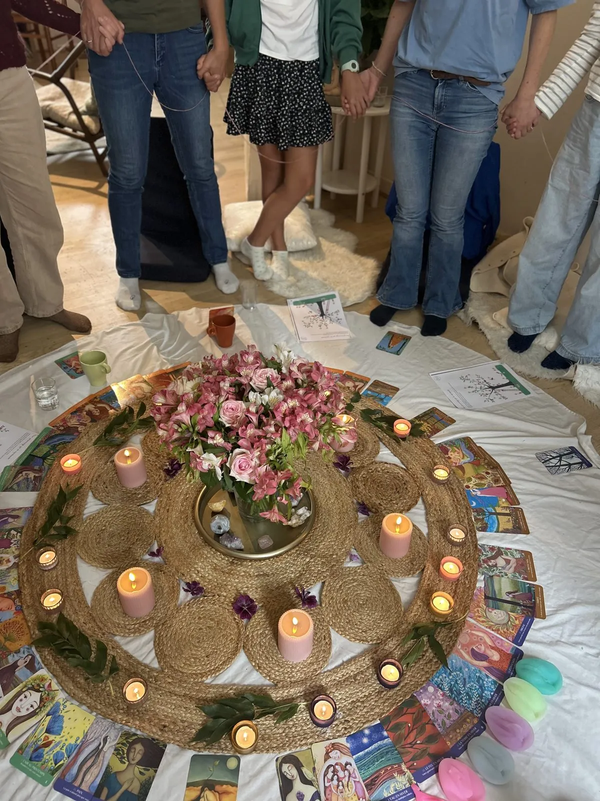 Mains reliées autour du cercle de bougies et de fleurs d’un Cercle Rose