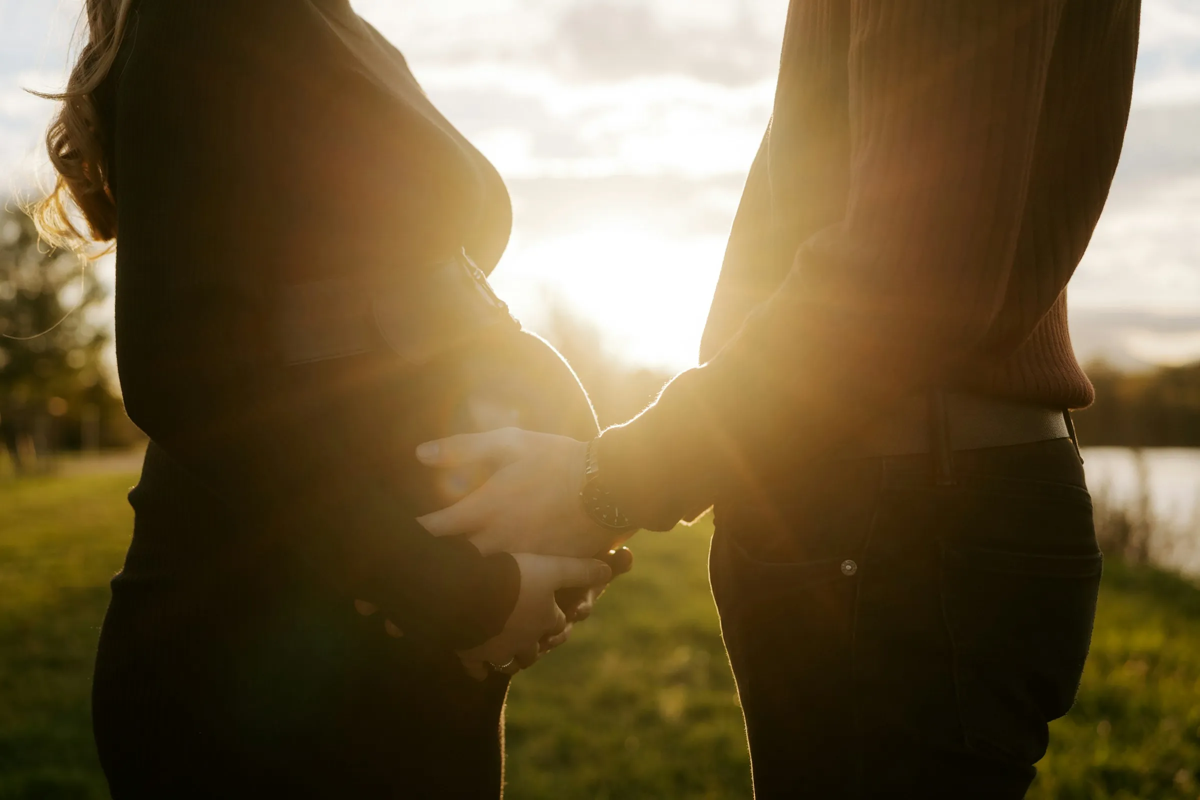 Couple tenant le ventre de la future mère au coucher du soleil