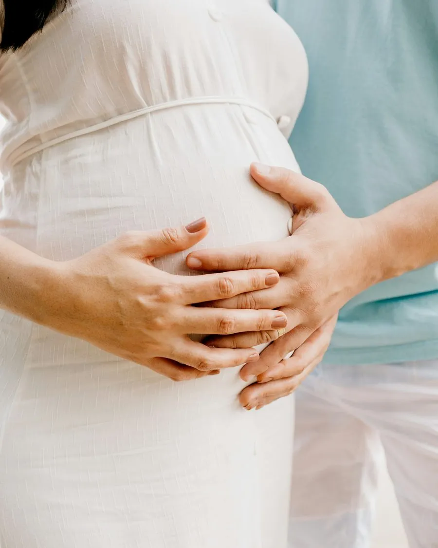 Les mains de la future maman et du coparent posées ensemble sur le ventre
