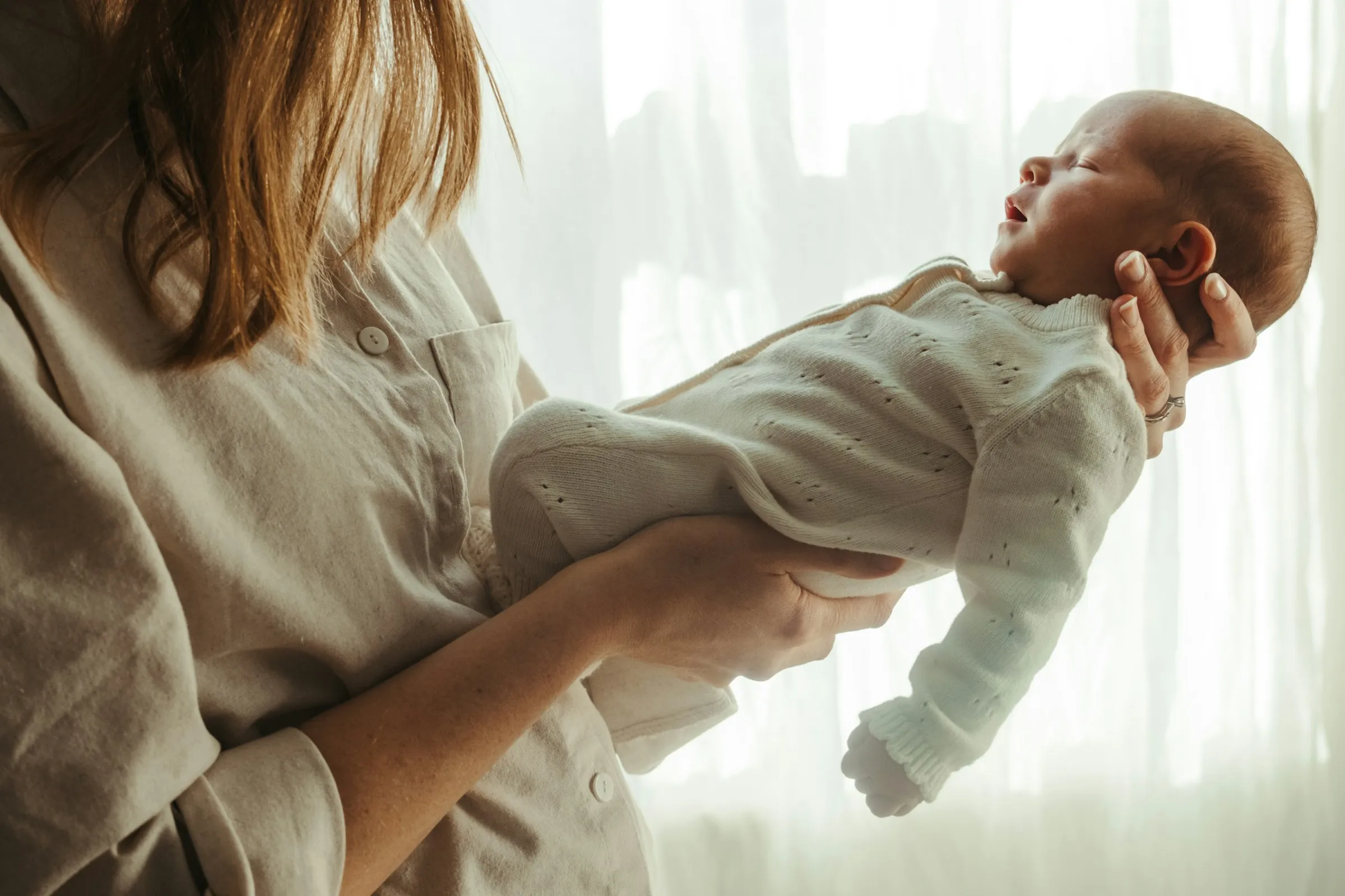 Mère tenant son nouveau-né près d’une fenêtre