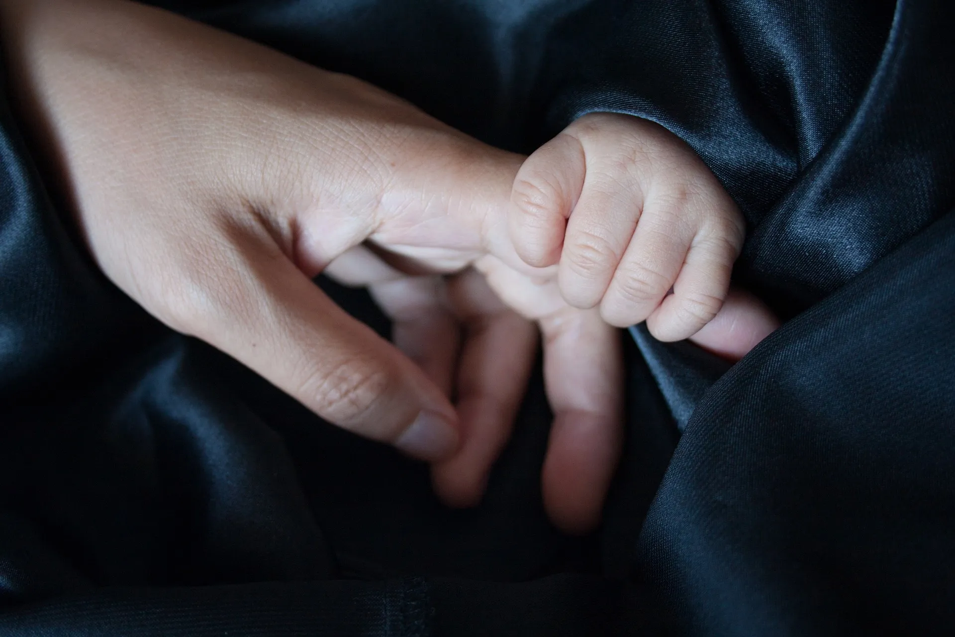 La main d’un bébé qui serre le doigt d’un adulte