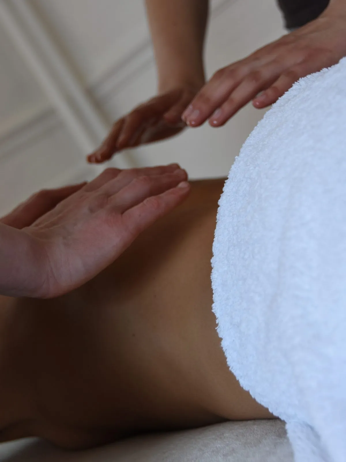 Quatre mains posées au-dessus du dos d’une femme pendant le Rituel Rebozo