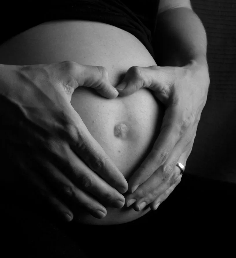 Mains formant un cœur sur un ventre de femme enceinte